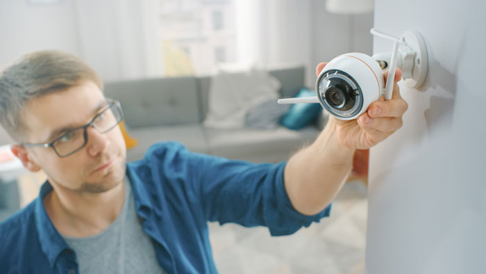 Man adjusting security camera inside home