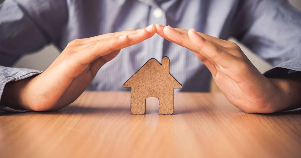 A homeowner covers a cut-out of a house with both his hands